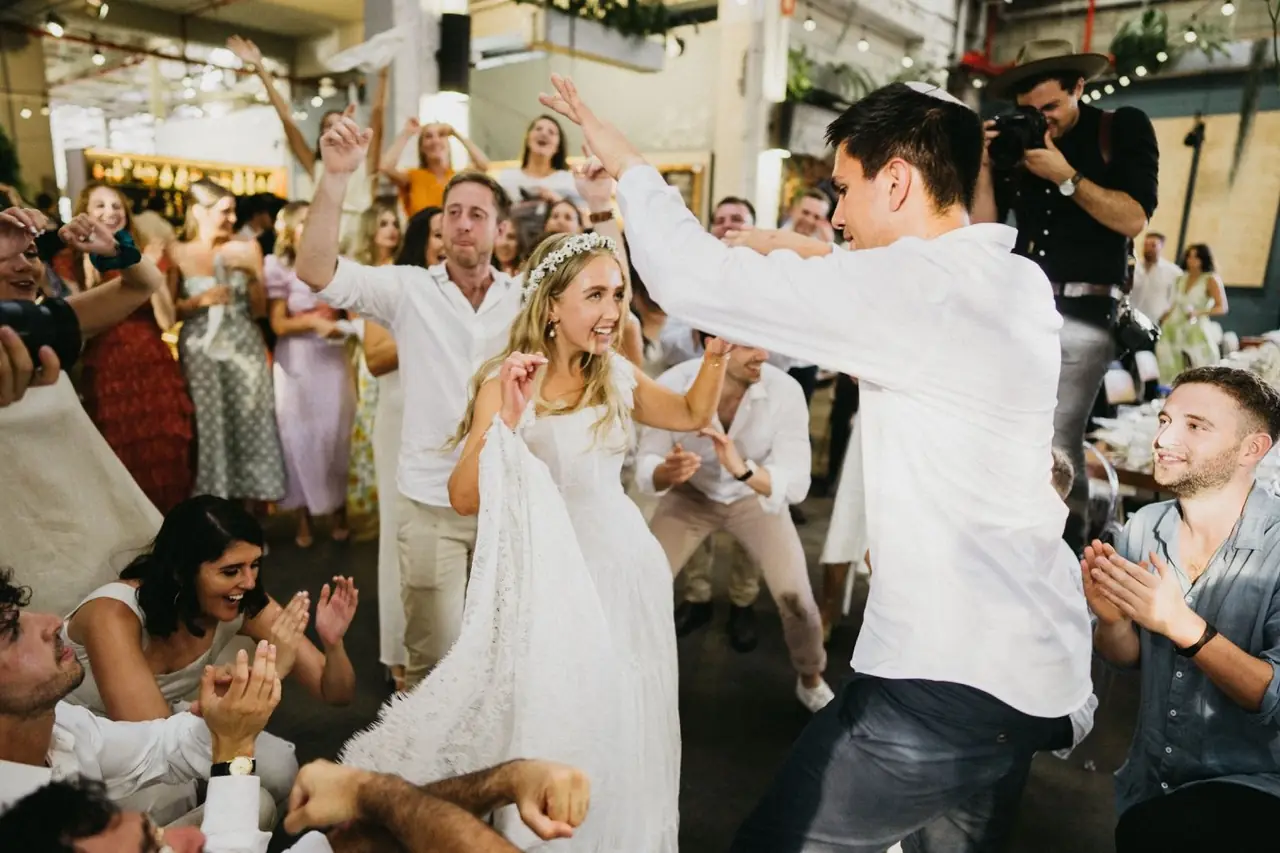 Tali & Jesse at Three Blue Ducks: The couple are lifted on chairs during the hora.
