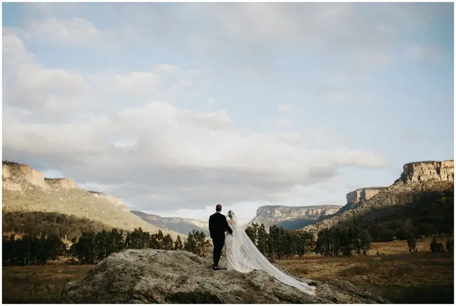 Tom & Josslyn at Emirates One&Only Wolgan Valley: A wide landscape photograph of the couple surrounded by the valley.