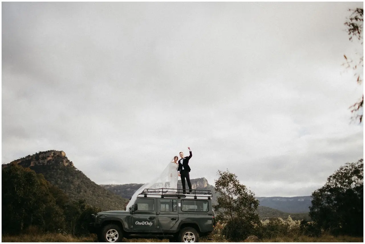 Tom & Josslyn at Emirates One&Only Wolgan Valley: The couple stand on a four-wheel drive beneath a dramatic sky.