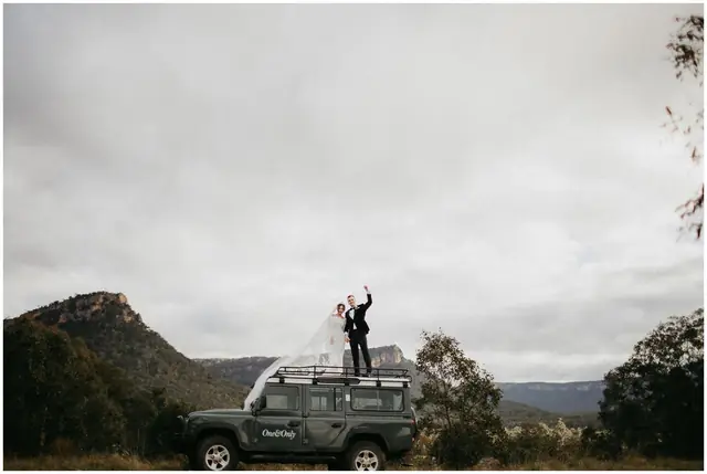Tom & Josslyn at Emirates One&Only Wolgan Valley: The couple stand on a four-wheel drive beneath a dramatic sky.