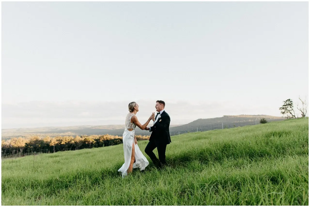 Ella & Jackson at The Woods: The couple walk together across a green paddock.