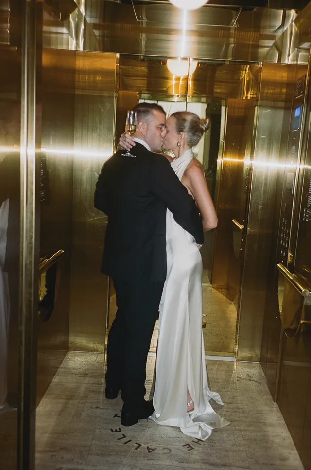 Clare and Matt kissing in the gold mirrored lift at The Calile Hotel in Brisbane.
